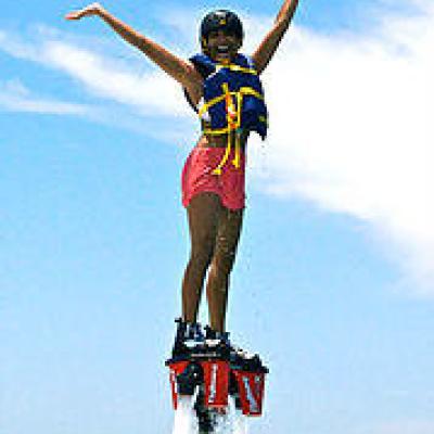 Woman in blue life jacket and pink shorts flyboading